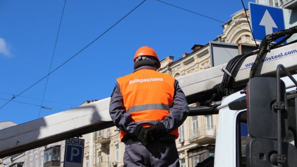 У Києві судитимуть підприємця за самовільне будівництво ресторану на березі Дніпра Працівник у жилеті з написом «Київреклама» стоїть біля автовишки на тлі історичних будівель Києва