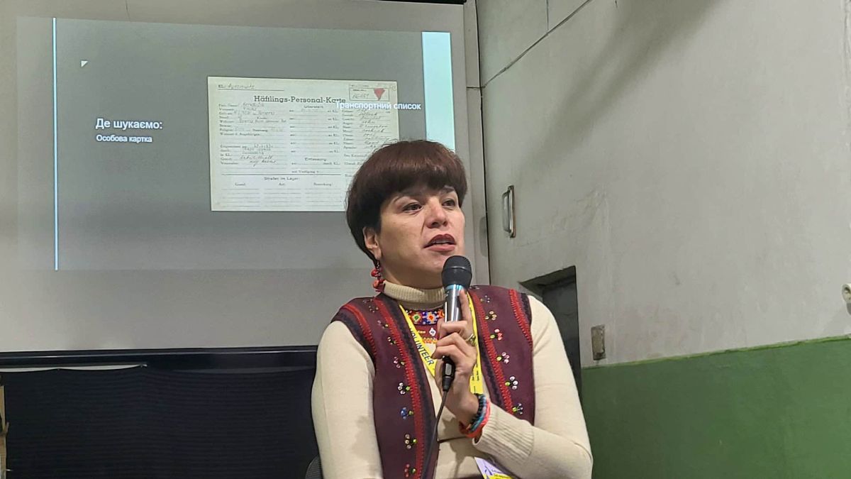 Близько 10 тисяч українців уже знайшли у списках в’язнів Аушвіцу Історикиня Олеся Ісаюк з мікрофоном читає лекцію про пошук українців у списках в’язнів Аушвіцу у Львові