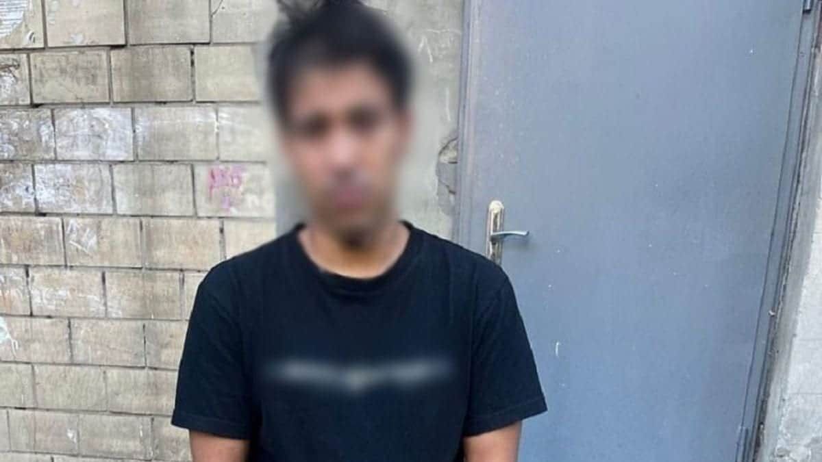 23-річний киянин сяде на 7 років за напад на пенсіонерку в Деснянському районі Молодий чоловік у чорній футболці стоїть біля стіни з металевими дверима