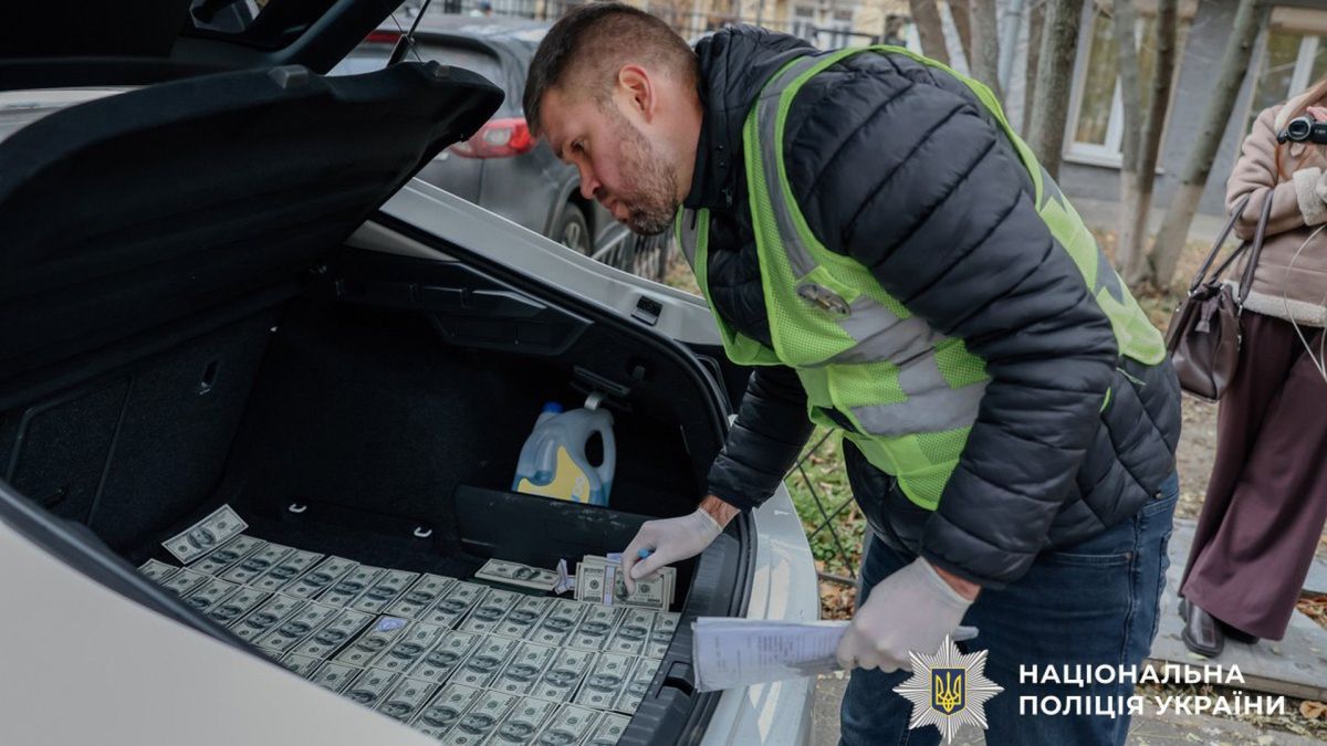 «Брат Єрмака» вимагав $100 тисяч за посаду в Офісі президента Поліцейський заглядає в багажник де розкладені доларові купюри