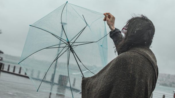 Пориви до 20 м/с: Укргідрометцентр попередив киян про сильний вітер Жінка тримає парасольку під час сильного вітру