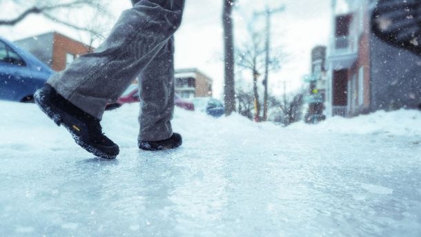 Мороз до -20° та туман: погода на Київщині 21 лютого Пішохід крокує по вкритому льодом тротуарі під час снігопаду — ілюстрація до прогнозу погоди про мокрий сніг та ожеледицю на Київщині