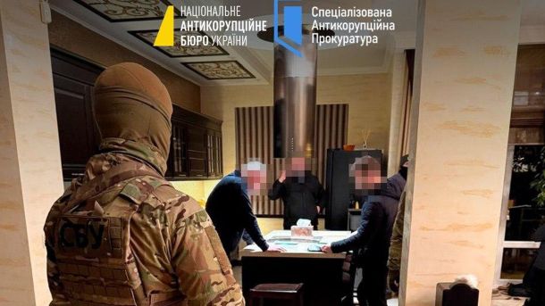 Київпастранс: очільник дирекції будівництва під слідством НАБУ Чотири чоловіки в помешканні, троє стоять біля стола і один біля входу в захисній військовій формі