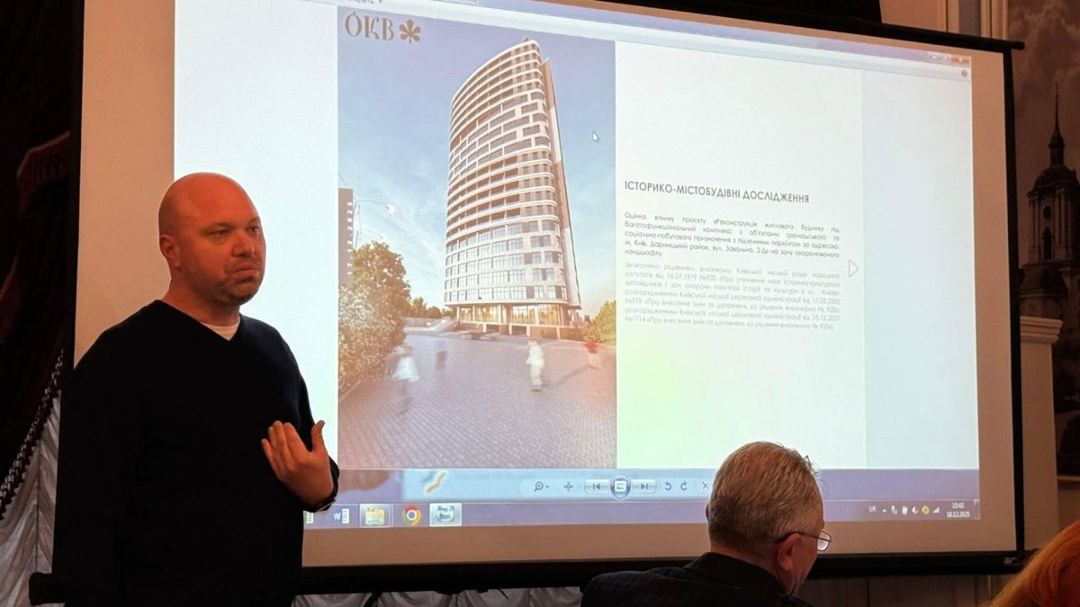Забудови найстарішої садиби на Осокорках: не буде — ДОКС Чоловік у чорному светрі презентує проєкт багатоповерхового житлового комплексу на тлі слайду з візуалізацією будівлі та історико-містобудівним дослідженням