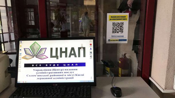 «Не мовчи, полон вбиває»: у Києві відбулася традиційна недільна акція підтримки Ноутбук стоїть на столі в ЦНАПі Соломʼянського району, біля ноутбука мишка від нього і видно відвідувачів через скляні двері