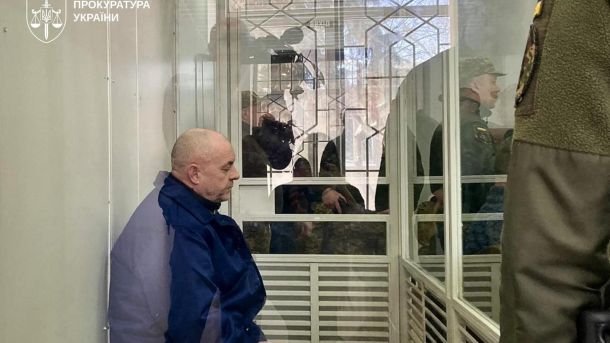 Тиждень у Києві: 8 тривог, 1200 дронів для бригади та дистанційне навчання Засуджений російський військовий у синій куртці сидить за склом у залі Шевченківського районного суду Києва, поруч конвоїр у формі