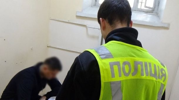 Пам'ятку на Андріївському узвозі дозволили розібрати Поліцейський у жилеті з написом Поліція стоїть спиною до камери, підозрюваний із заблюрованим обличчям сидить нахилившись у приміщенні відділку
