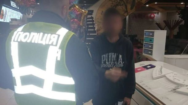 Загуменного звільнили з-під домашнього арешту і повернули на посаду Поліцейський у жилеті спілкується з чоловіком у кофті з розмитим обличчям у ТРЦ