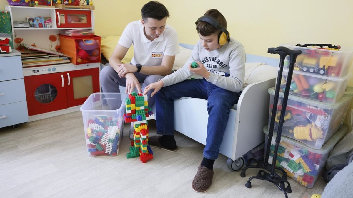 У Києві в центрі «Особлива дитина» облаштували укриття, сполучене з лікарнею (фото) Терапевт працює з дитиною в навушниках, будуючи конструкцію з кольорових блоків у кімнаті