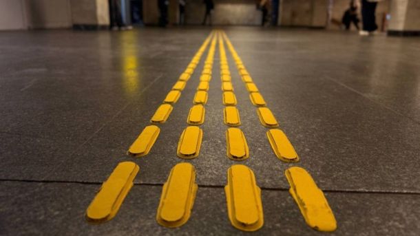 На станції метро «Політехнічний інститут» стартував проєкт про внесок КПІ у розвиток Києва Жовта тактильна смуга для людей із вадами зору на темній підлозі підземного переходу чи станції метро