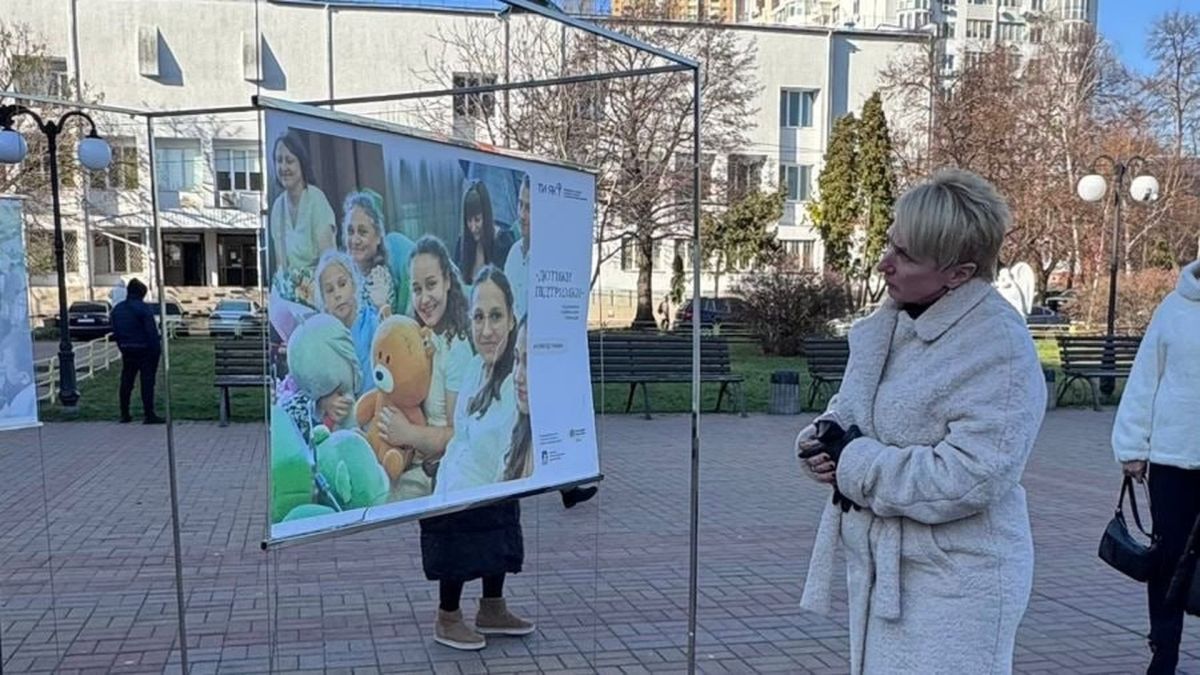 Просто неба у Вишгороді показують фото з виставки «Дотики підтримки» Жінка роздивляється фотографію на площі у Вишгороді