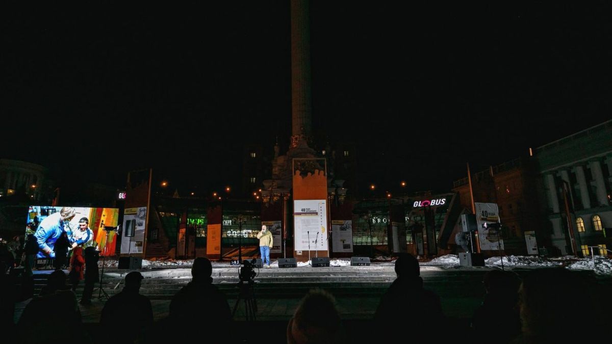 «Територія Гідності»: вечір пам'яті на Майдані Виступ на сцені під час вечора пам'яті «Територія Гідності» на Майдані Незалежності вночі, виставкові панелі та монумент на фоні