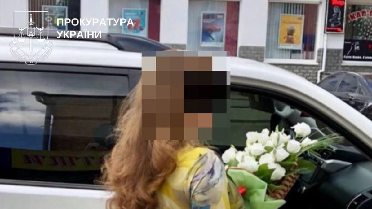 На Білоцерківщині відсторонили реєстратора за привласнення шкільного стадіону Жінка з розмитим обличчям у квітчастому вбранні з букетом білих троянд біля автомобіля — підозрювана у справі про привласнення шкільного стадіону