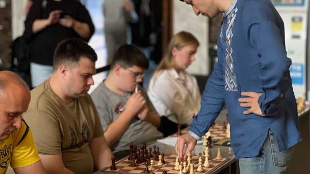 На київському вокзалі шахістка перемогла міжнародного майстра Павлова Група людей грає у шахи в громадському місці, під час турніру або тренування, зосереджено та серйозно налаштовані.