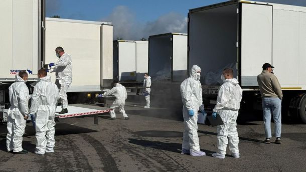 Київ: майже 90% житлових будинків готові до опалювального сезону Люди у білих захисних костюмах та масках працюють біля відкритих вантажівок-рефрижераторів