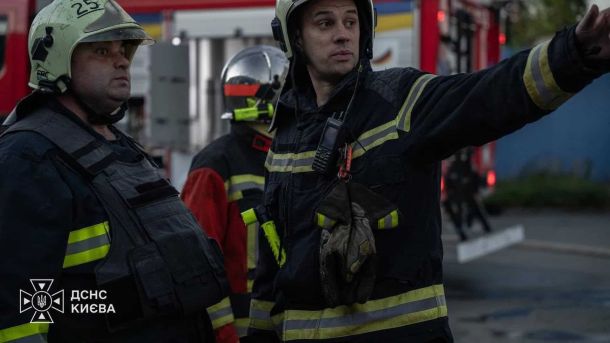 Уламки впали на приватний будинок у Дніпровському р-ні, двоє поранених Рятувальник ДСНС Києва у захисному спорядженні показує рукою напрямок біля пожежної машини на місці ліквідації наслідків атаки