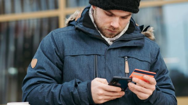 Міжнародні потяги з Києва переведуть на контроль у русі без зупинок на кордоні Чоловік в куртці і шапці стоїть на вулиці з мобільним телефоном в руках