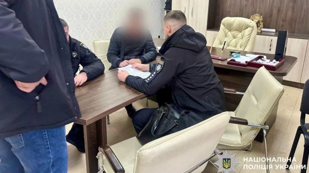 Чиновницю на Броварщині підозрюють у махінаціях на 1,5 млн грн Правоохоронці сидять за столом в офісі поряд із підозрюваним у скоєнні злочину