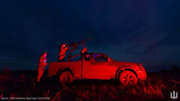 На Оболоні понівечило техніку після нічної атаки дронів Українські військові в червоному світлі біля пікапа з кулеметом у кузові під зоряним небом