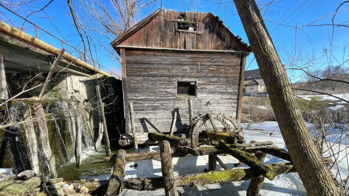 Останній дерев'яний млин Київщини оцифрували для реставрації Старий дерев'яний водяний гребляний млин у селі Семенівка Обухівської громади — будівля на палях над замерзлою річкою Красна, дерев'яні колеса, зима 2026 року