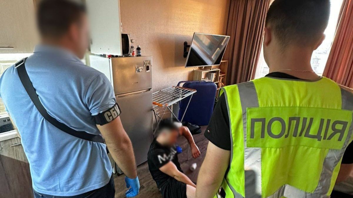 У Києві затримали організатора втечі за кордон за $20 тисяч Поліція прийшла додому до підозрюваного, він сидить на підлозі, обличчя заблюрене, двоє працівників поліції стоять поруч