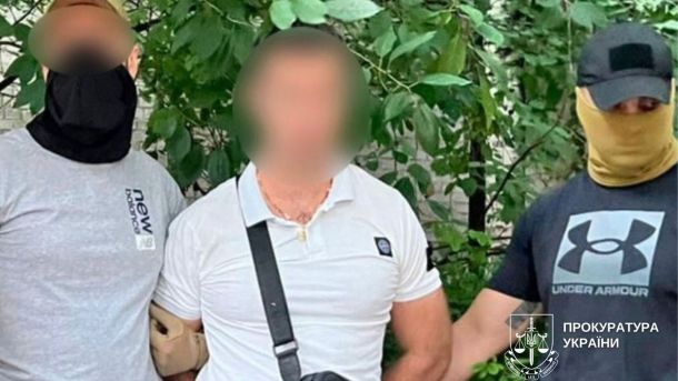 На Київщині прогнозують заморозки до -3°: оголошено жовтий рівень небезпеки У центрі чоловік у білій футболці з розмитим обличчям, по обидва боки від нього стоять двоє правоохоронців у масках