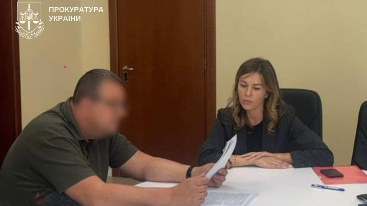 У Києві судитимуть посадовців за переплату 51 млн грн Жінка слідча вручила підозру чоловіку і дивиться як він читає документ, вони обидвоє сидять за столом в кабінеті