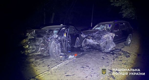 На Борщагівці затор через ДТП на вулиці Симиренка: рух ускладнений Велика дорожньо-траспортна аварія з пошкодженими автомобілями на темній вулиці вночі, з червоними і чорними авто, поліція України на місці події.
