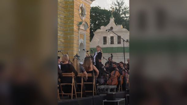 «Софія Київська» відкриває виставку Хижинського до його 55-ліття Диригентка та оперна співачка на сцені просто неба біля Успенського собору Києво-Печерської лаври, на фоні оркестр і глядачі
