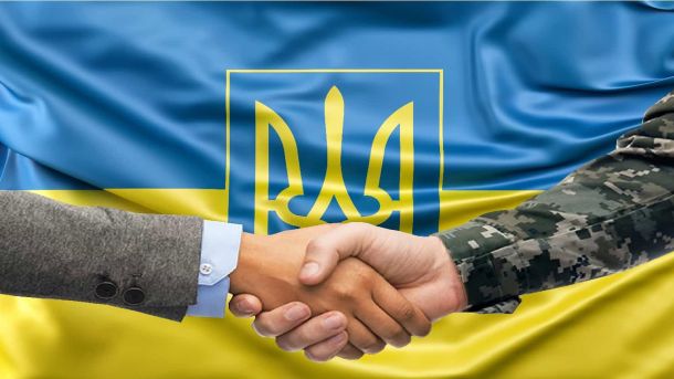 У Києві викрили банду колишніх «смотрящих» СІЗО Ветеран у військовій формі та цивільний потискають руки на тлі державного прапора України з тризубом
