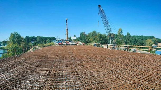 Біля ЖК River Stone демонтували паркан і відкрили 500 метрів набережної Дніпра будівництво мосту з арматурним каркасом, працює будівельна техніка та крани