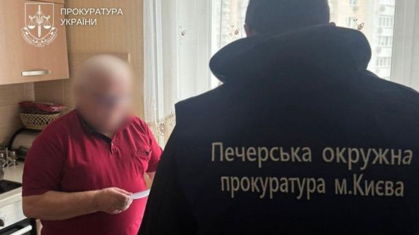 З 2026-го акцизи на сигарети зростуть на 5% — депутат ВР Чоловік в червоній кофті тримає в руках папір і читає його, біля нього стоїть працівник прокуратури