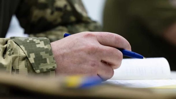 У КПІ відкрили сучасне укриття для 150 осіб у 18-му корпусі Військовий у камуфляжі пише ручкою в блокноті