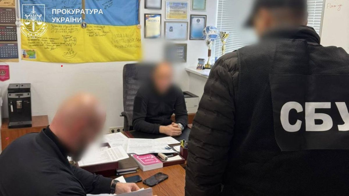 Київську митницю спіймали на хабарі: $2400 за авто Троє чоловіків в кімнаті, двоє з них із заблюреними обличчями. На фоні одного з них прапор України