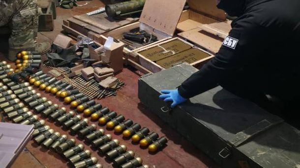 10 000 доларів за зняття з розшуку в «Оберіг»: на Київщині затримали офіцера-хабарника Набої, гранатометні постріли та металеві ящики з боєприпасами на столі під час обшуку в київському автосервісі, працівник СБУ у блакитних рукавичках
