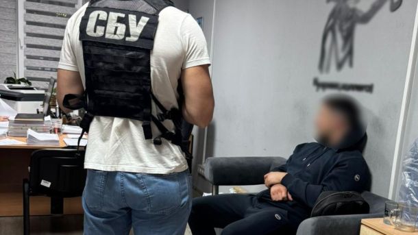 У Києві викрили організаторів схем із втечею за кордон та фіктивним бронюванням На передньому плані видно працівника у бронежилеті з написом «СБУ», поруч сидить чоловік