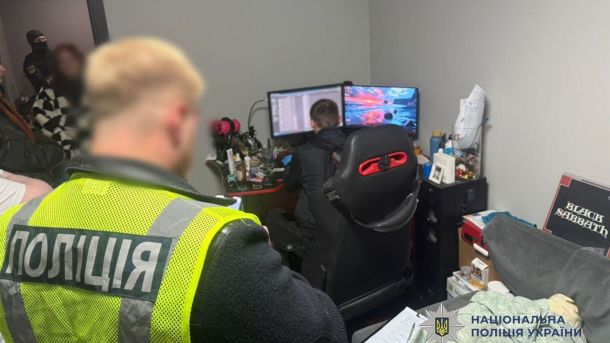 У Києві відкрили Хаб стійкості Сіверськодонецької громади Поліцейський у яскравому жилеті проводить обшук у кімнаті, де чоловік сидить за комп’ютером із двома моніторами