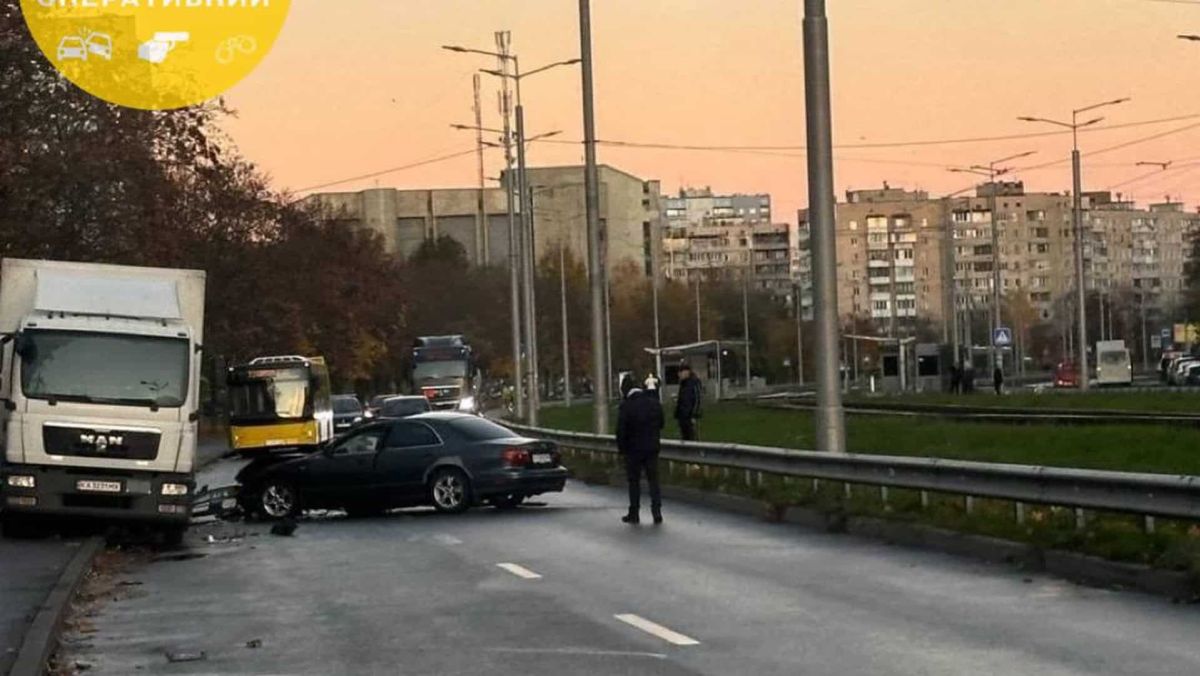 На Борщагівці затор через ДТП на вулиці Симиренка: рух ускладнений Чорне авто врізалося в вантажівку на дорозі, поруч люди