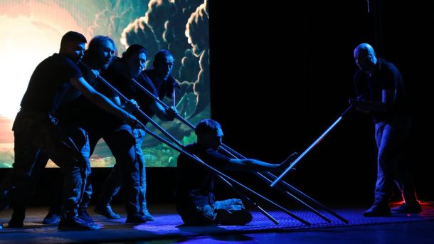 Київські театри підняли ціни на квитки: де та на скільки подорожчало Чоловіки із палицями на сцені театру в темному освітленні, це вистава "Енеїда"