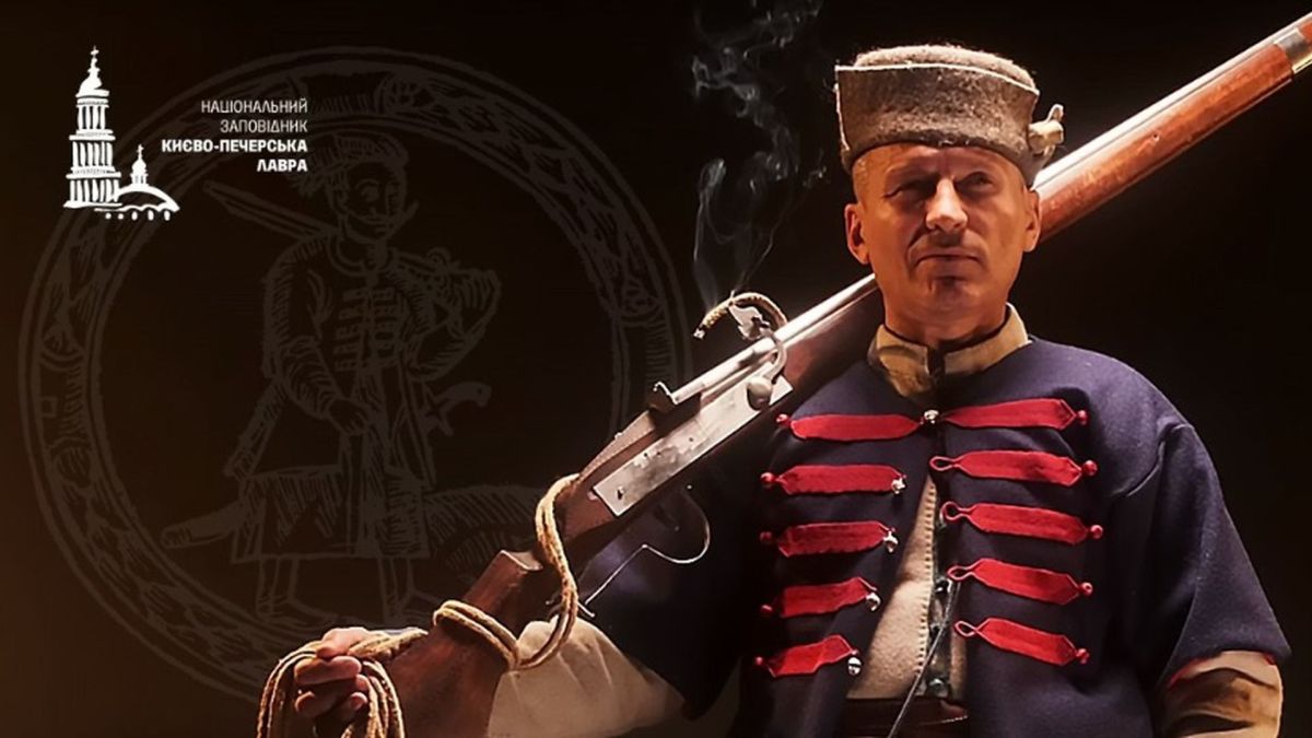 У Лаврі демонструють одяг XVII століття: жупани можна буде приміряти Чоловік у козацькому строї з рушницею на плечі стоїть на темному фоні з гербом