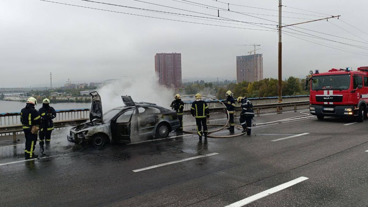 На Північному мосту загорілось авто під час руху Пожежники гасять пожежу на мосту, горить автомобіль, на фото декілька пожежників