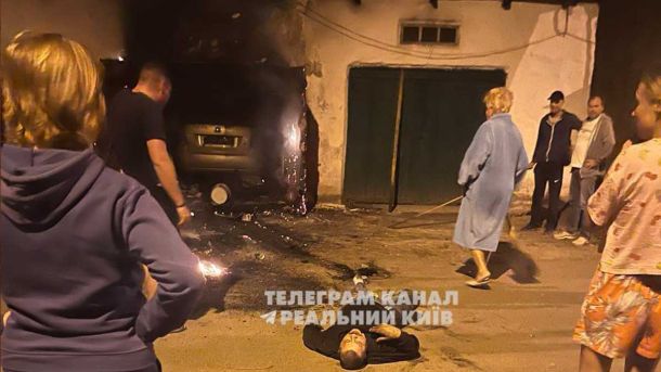 Що сталося в Коцюбинському: чоловік підпалив гараж із людиною всередині чоловік лежить на землі, навколо люди, спалений гараж