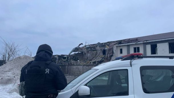 ДСНС: на Київщині ліквідували наслідки комбінованої атаки (фото) Поліцейський у чорній формі оглядає зруйнований будинок після атаки на Київщину, поруч патрульне авто