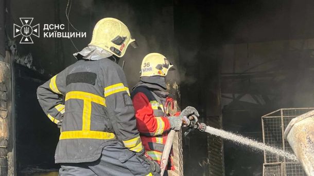Бориспільський район: ДСНС залучила авіацію для гасіння пожеж після обстрілу Двоє рятувальників ДСНС подають воду зі шланга в осередок пожежі на території складу торговельної мережі в Бучанському районі