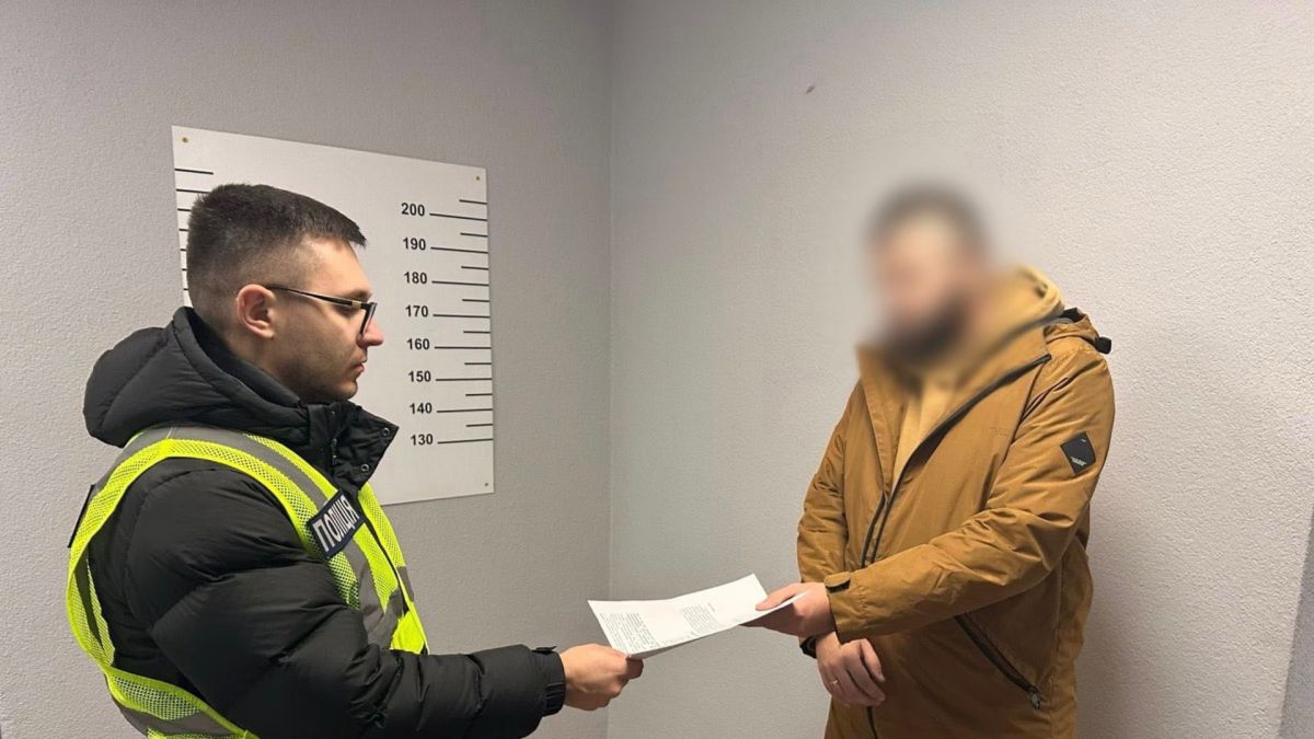 На Київщині двоє чоловіків обіцяли зняти військовозобов'язаних з розшуку в ТЦК за 20 тис грн Поліцейський у відділку поліції вручає підозрюваному документ
