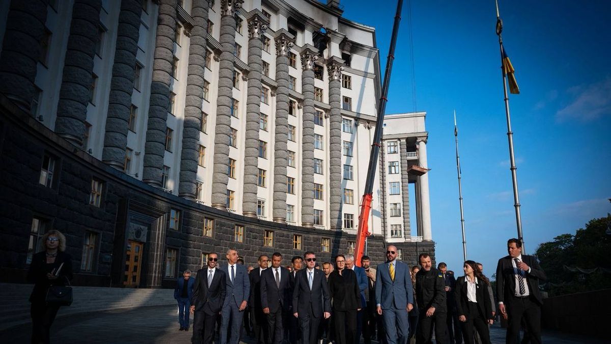 Іноземним дипломатам у Києві показали пошкодження будівлі Кабміну Київська міська рада під час офіційної церемонії з підняттям державного прапора на високому флагштоку в центрі Києва, сучасний урядовий complex, робочий день у центрі міста, офіційні особи у костюмах.