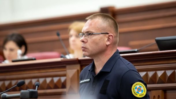 На Подолі забудовник ігнорує заборону та проводить роботи в Будинку з хлібною лавкою Чоловік у формі служби порятунку стоїть у залі засідань із мікрофонами