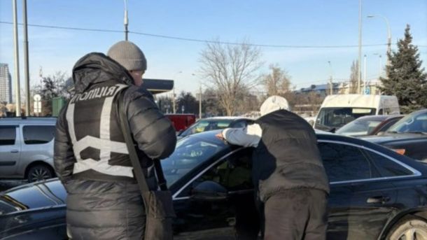 У КМДА викрили чиновника з 22 млн заощаджень без доходів Поліцейський і підозрюваний біля автомобіля