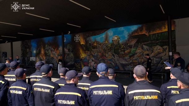 День учителя під обстрілами: освітяни відзначають свято після нічної атаки на українські міста Працівники ДСНС біля великого муралу, присвяченого рятувальникам