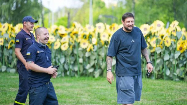 Водія з ознаками наркосп'яніння, позбавленого прав, зупинили на Печерську Пожежники ДСНС і чоловік у спортивному одязі усміхаються на тлі лабіринту з соняшників на фестивалі ВДНГ